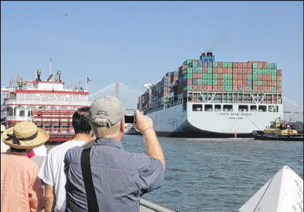  ?? J. SCOTT TRUBEY / STRUBEY@AJC.COM ?? The Cosco Developmen­t cargo ship passes a crowd gathered on River Street in Savannah on Thursday. The ship is moving on to the Garden City Terminal on the Savannah River.