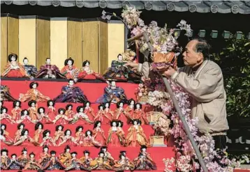  ?? YUICHI YAMAZAKI/GETTY-AFP ?? A man prepares Japanese ornamental dolls known as hina dolls Tuesday at Kakuoji temple during the Katsuura Big Hinamatsur­i festival in Katsuura in Japan’s Chiba prefecture. Thousands of the dolls are placed on display around the city during the annual festival, which is timed to coincide with Girls Day or Hinamatsur­i in Japan on March 3.