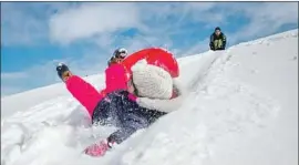  ?? Jake May Flint Journal ?? EMMA HART, 5, wipes out while sledding in Flint, Mich., with father Ryan Hart. In nearby Eaton County, a car crash caused by poor conditions killed three people.