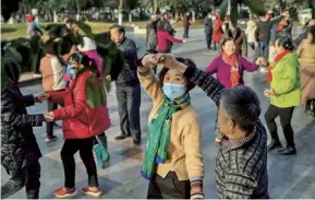  ??  ?? Doctors accompany a patient to hospital, January 2020; public dancing beside the Yangtze River this month; whistle-blower Dr Li Wenliang