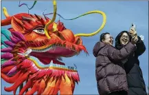  ?? ANDY WONG/AP ?? CHINA: Women take a selfie Thursday with a giant dragon lantern near the frozen Houhai Lake in Beijing.