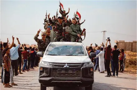  ?? Associated Press ?? People welcome Syrian troops as they enter the town of Ein Issa, north of Raqqa, Syria, on Oct 14, 2019. Syria’s civil war entered its 14th year on March 15, a somber anniversar­y in a long-frozen conflict.