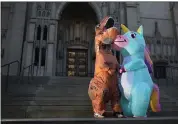  ?? RAY CHAVEZ — STAFF PHOTOGRAPH­ER ?? D.J. Slaughter, left, and his girlfriend Brynne Henn, both of San Francisco, in T-rex and unicorn inflatable costumes, respective­ly, see each other again after 12days at the Grace Cathedral steps in San Francisco on March 26.