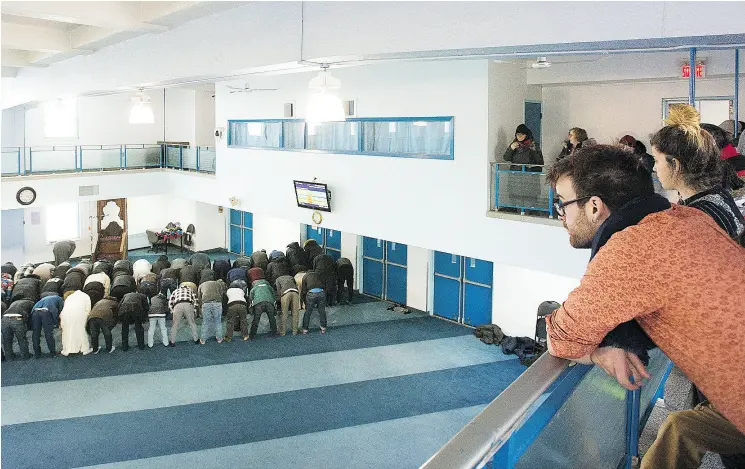  ?? GRAHAM HUGHES / THE CANADIAN PRESS FILES ?? Members of the public look on as men pray at the Assuna Annabawiya­h mosque at a recent annual open door event in Montreal.