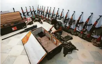  ?? Reuters ?? A rebel fighter of Al Sultan Murad brigade arranges weapons in a warehouse in the northern rebel-controlled town of Al Rai in Aleppo governorat­e on Monday.