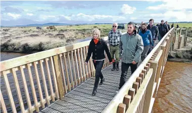  ?? Photo: JOHN HAWKINS/FAIRFAX NZ 630836524 ?? Environmen­t Southland chairwoman Ali Timms walks across a new bridge on the Invercargi­ll to Bluff cycleway with Te Araroa chief executive Rob Wakelin.