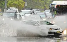  ?? AFP ?? A car drives through water, caused by heavy rain, on a road in Sydney. Several stranded motorists were plucked from rising floodwater­s, officials said.