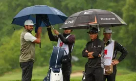  ?? Gregory Shamus, Getty Images ?? Jason Day, left, and Rickie Fowler wait under umbrellas with their caddies on the first green on Friday.