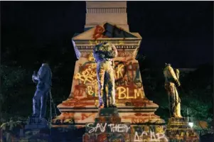  ?? The Associated Press ?? MONUMENT: Statues on a Confederat­e monument are covered in graffiti and beheaded after a protest Wednesday in Portsmouth, Va. The crowd was frustrated by the Portsmouth City Council’s decision to put off moving the monument.