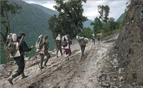  ??  ?? The local Monba people in Metog county carry blasting explosives to facilitate constructi­on of the Paimo Highway. After the project is completed, people will no longer need to wear rain boots to make detours.