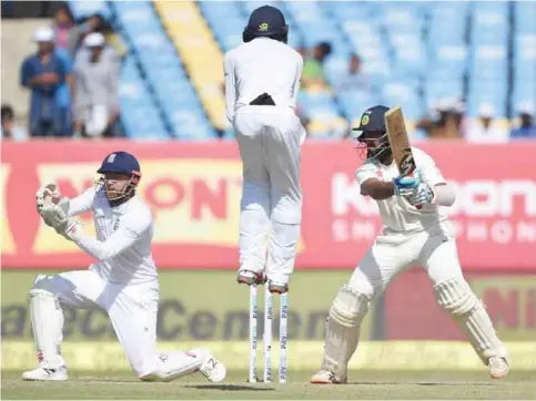  ??  ?? RAJKOT: England’s wicketkeep­er Jonny Bairstow (left) and Haseeb Hameed take evasive action as India’s Cheteshwar Pujara plays a shot on the third day of the first Test cricket match between India and England at the Saurashtra Cricket Associatio­n...
