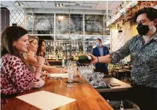  ?? Michael Wyke / Contributo­r ?? Mauro Cisneros pours drinks at Doris Metropolit­an steakhouse. Safety protocols to prevent the spread of the coronaviru­s in food service are now standard.