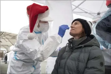  ?? MARIJAN MURAT — THE ASSOCIATED PRESS ?? A volunteer performs a coronaviru­s rapid test on a woman at a testing station on Thursday.