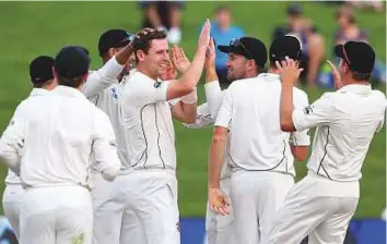  ?? AFP ?? Matt Henry (centre) of New Zealand celebrates with teammates after taking the wicket of Temba Bavuma of South Africa during day four of the third Test in Hamilton yesterday.