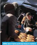  ?? ?? ARIHA, Syria: A Syrian youth buys bread at a market in this town in rebel-held northweste­rn Idlib province on [OL ÄYZ[ KH` VM 9HTHKHU VU 4HYJO · (-7