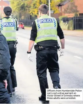  ??  ?? Officers from Humberside Police carry out a drug warrant on Victor Street in Grimsby where three adults were arrested.