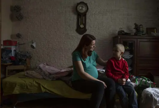  ?? Nariman El-mofty, The Associated Press ?? Marta Kopan, pictured at 38 weeks pregnant on April 3, talks to her 6-year-old son Nazar, at an apartment in Lviv, Ukraine, given to them by a cousin after they fleed their home in Kyiv. The place in Kyiv where Marta was meant to give birth was bombed. Her birth plan, like almost everything else, was left behind.