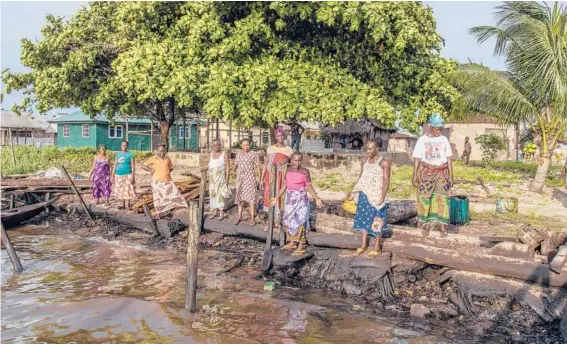  ?? YAGAZIE EMEZI/THE NEW YORK TIMES PHOTOS ?? Fisherwome­n survey the remnants of the crude oil that remains from a spill near Warri, Nigeria, after their protest forced Chevron to take action.