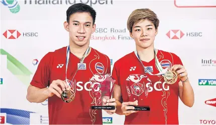  ??  ?? Dechapol Puavaranuk­roh, left, and Sapsiree Taerattana­chai pose with their mixed doubles gold medals and trophies.