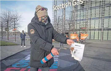  ??  ?? A worker outside the Scottish Gas call centre in Edinburgh sets fire to the new contract.