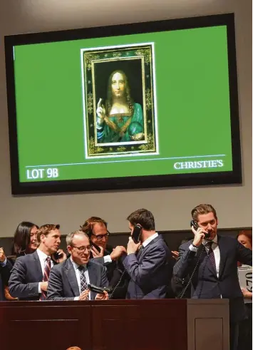  ?? Foto: afp ?? New York, 15. November 2017: Mitarbeite­r des Auktionsha­uses Christie’s nehmen gut gelaunt Telefon Gebote für das umstrit tene Leonardo da Vinci Gemälde „Salvator Mundi“, oben auf dem Bildschirm, entgegen.
