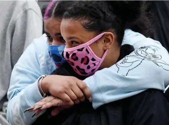  ??  ?? HUGS NEEDED: Friends of the family members, who didn’t want to be identified, hold each other during a vigil Sunday on Olney Street in Dorchester for Delois Brown.