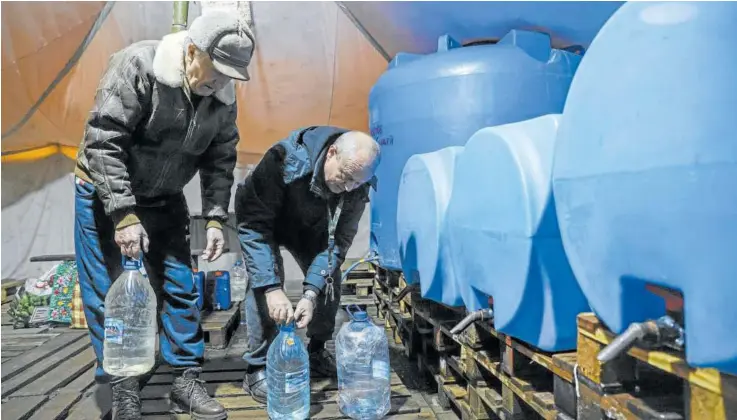  ?? Foto: Efe ?? Dos civiles llenan de agua bidones de plástico en Donetsk al estar cortado el suministro de agua potable en la red.