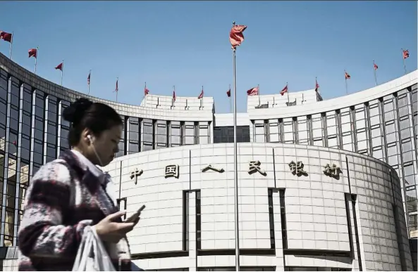  ?? — Bloomberg ?? Trade talks: A woman walks past PBoC headquarte­rs in Beijing. The Chinese government is in talks with Japan as well as European and Asean countries about bilateral trade and investment agreements, but is waiting for the new US administra­tion to decide...