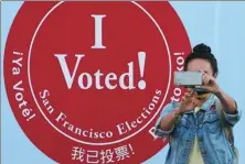  ?? JEFF CHIU / ASSOCIATED PRESS ?? A woman takes a photo in front of an “I Voted” sign at a voting center in San Francisco on Monday.