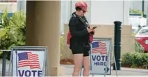  ?? JOE CAVARETTA/
SOUTH FLORIDA SUN-SENTINEL ?? A voter checks her phone before voting in the Florida primary election at the Boca Raton Public Library in Boca Raton on Aug. 23.