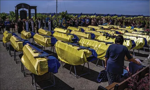  ?? PHOTOS BY WOJCIECH GRZEDZINSK­I/THE WASHINGTON POST ?? The caskets of 27 Ukrainian serviceman who died fighting the Russians are draped in Ukrainian flags. New protocols are on display at military funerals that reflect Western customs, such as those followed by the U.S., and uniquely Ukrainian traditions, instead of those inherited from Russia.