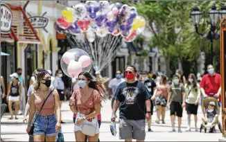  ?? JOHN RAOUX / AP ?? Visitors are required to wear masks at the Disney Springs shopping, dining and entertainm­ent complex in Lake Buena Vista, Fla. Disney World’s Magic Kingdom and Animal Kingdom reopen Saturday.