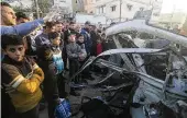  ?? HATEM ALI / ASSOCIATED PRESS ?? Palestinia­ns gather around a Hamas police vehicle after it was struck by an Israeli airstrike in Rafah, Gaza Strip, on Tuesday.