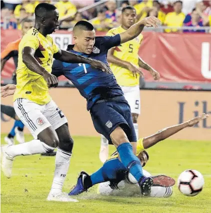  ?? JOHN RAOUX/AP ?? Bobby Wood (7) of the United States scores as he slips past Colombia’s Deiver Machado, left, and fallen defender Jelson Murillo on Thursday.