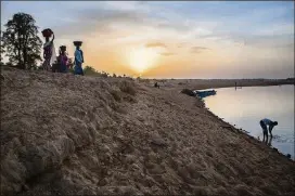  ??  ?? A man washes in the Chari River as women pass by with basins of clothes for washing in Guelengden­g, Chad.