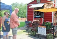  ?? Photos by Diane Wagner ?? BELOW: Rebecca Kelley (left) of Anniston, Ala., and Bruce Schumaker of Jacksonvil­le, Ala., check out Country Cabin’s 1929 John Deere engine hooked up to an ice cream churn Sunday at Rolater Park.