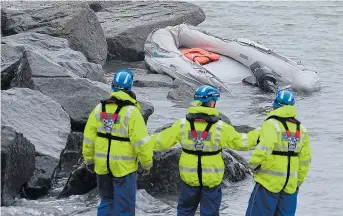  ??  ?? Warming up...two of the seven Iranian immigrants who were picked up at Samphire Hoe, near Dover, on Friday. Rescuers, above, survey their sinking inflatable craft