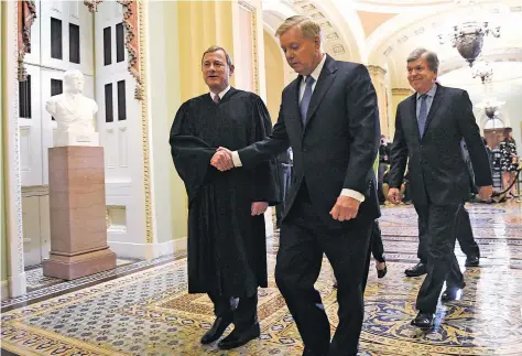  ?? SUSAN WALSH/ASSOCIATED PRESS ?? Sen. Lindsey Graham, R-S.C., center, shakes hands Wednesday with Supreme Court Chief Justice John Roberts as they walk out of the Senate Chamber on Capitol Hill following a vote to acquit President Donald Trump, pictured top, on both articles of impeachmen­t. Sen. Roy Blunt, R-Mo., follows at right.