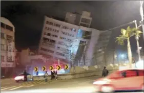  ?? PHOTO/HUALIEN COUNTY FIRE BUREAU ?? In this photo released by Hualien County Fire Bureau, rescuers are seen entering an building that collapsed onto its side from an early morning earthquake in Hualien County, eastern Taiwan on Wednesday. A 6.4-magnitude earthquake has struck eastern...