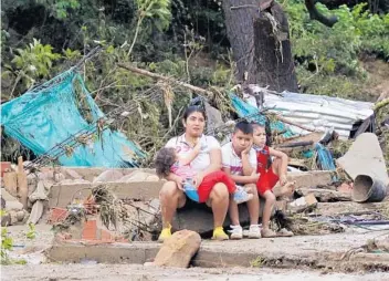  ?? SCHNEYDERM­ENDOZA/GETTY-AFP ?? Awomanand kids sit on the remains of a house destroyed by heavy rainsWedne­sday inCucuta, Colombia. Iota dissipated over El Salvador, but the storm’s rains remained a threat to the already drenched region.