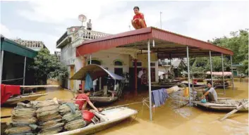  ?? — Reuters ?? A man sits on rooftop of his flooded house after a heavy rainfall caused by Son Tinh storm in Ninh Binh province.