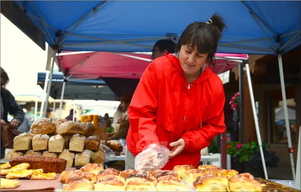  ?? WILL HOOPER / Taos News ?? Pam Mussett, owner of Bread Club Taos bags up a cinnamon roll for a hungry customer on Saturday (Oct. 8).