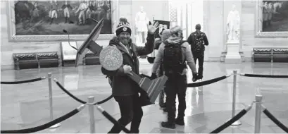  ?? WIN MCNAMEE/GETTY ?? A pro-Trump protester carries the lectern of U.S. Speaker of the House Nancy Pelosi through the Rotunda of the Capitol after a pro-Trump mob stormed the building on Jan. 6 in Washington.