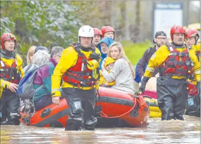  ?? Ben Birchall The Associated Press ?? Rescue operations continue Sunday as emergency service workers take residents to safety in Nantgarw, Wales.