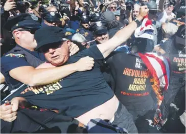  ??  ?? In this July 20 photo, a law enforcemen­t officer takes Gregory “Joey” Johnson into custody after he started to burn an American flag in Cleveland. President-elect Donald Trump said Tuesday that anyone who burns an American flag should face unspecifie­d...