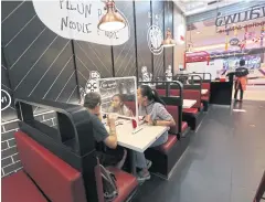  ?? VARUTH HIRUNYATHE­B ?? A family dines at a restaurant in a Bangkok department store with a shield in place to prevent the spread of Covid-19.