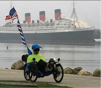  ??  ?? A cyclist pedals past Shoreline Aquatic Park with the Queen Mary in the background. — MARK BOSTER/TNS