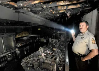  ?? NWA Democrat-Gazette/ANDY SHUPE ?? Monte Fuller, superinten­dent of Devil’s Den State Park, tours the 80-year-old Civilian Conservati­on Corps building at the park Friday, a day after the building,which housed a cafe and store, caught fire.