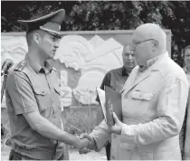  ??  ?? Подполковн­ик Александр лобанов передает медальон и архивные документы игорю буланцеву