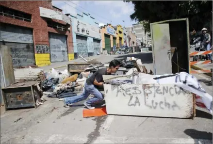  ?? ARIANA CUBILLOS — THE ASSOCIATED PRESS ?? An anti-government demonstrat­or pushes an old refrigerat­or to make a barricade on Saturday to protest against President Nicolas Maduro’s plan to rewrite the constituti­on in Caracas, Venezuela. The country is voting today on Maduro’s plan despite...